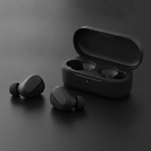 Ecouteurs intra-auriculaires noirs poses a cote de leur boitier de charge noir mat ouvert